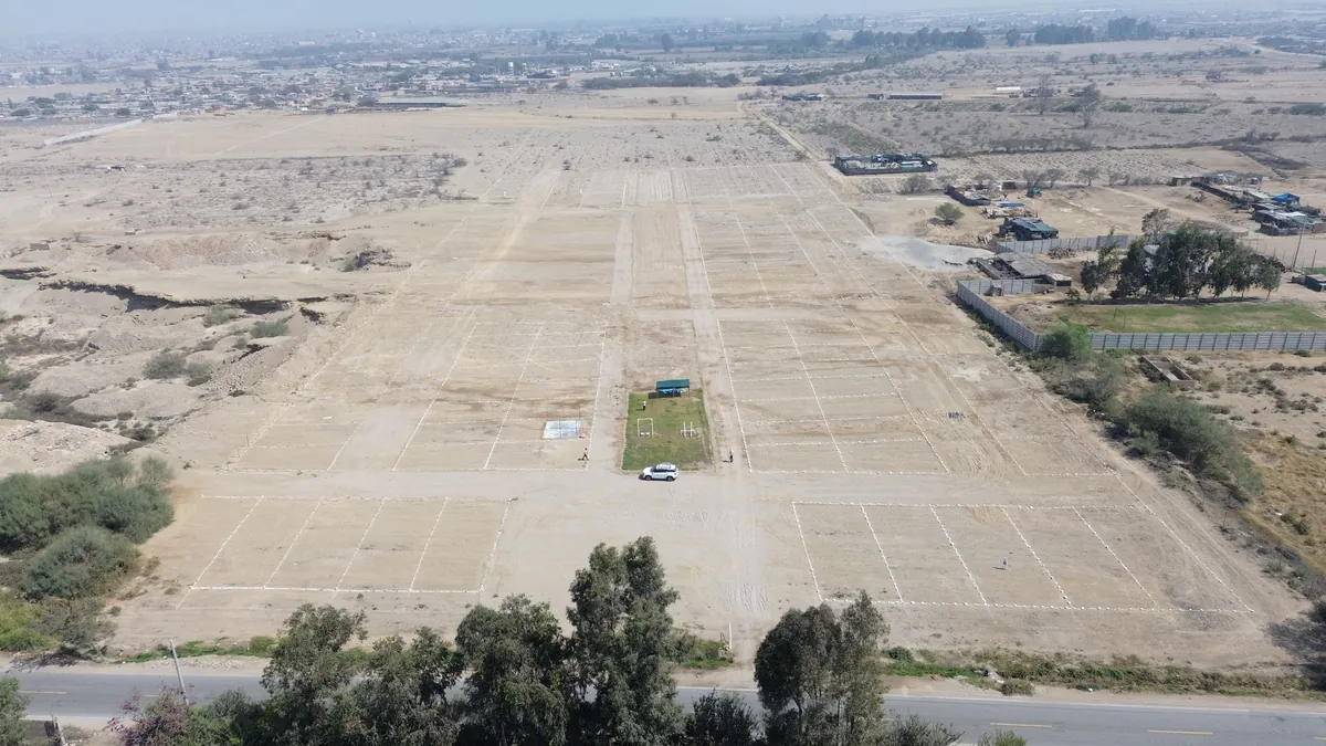 Vista aérea del avance real del proyecto El Lucero de Chincha: movimiento de tierras y lotización marcada sobre la Carretera Huancavelica